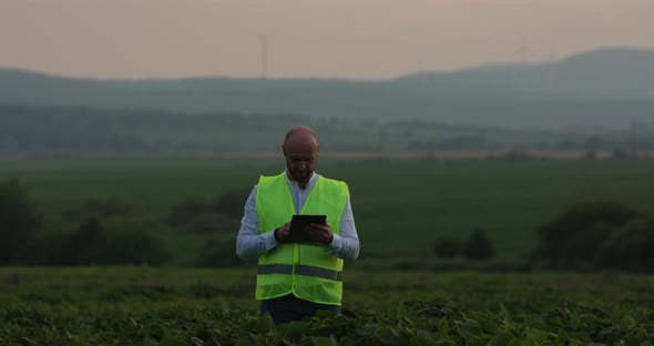 Agricultural Industry. A Male Farmer with a Digital Tablet in a Field at Sunset. Agronomist Uses