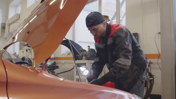 Mechanic Examining Car Engine in Auto Repair Shop