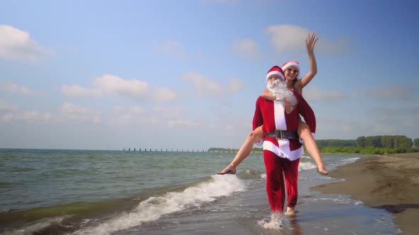 Girl riding Santa Claus by sea on shore on sunny day