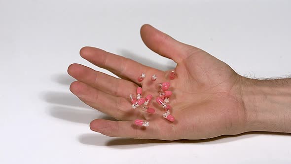 700366 Hand of Man Falling with Capsules of Morphine against White Background, Slow Motion