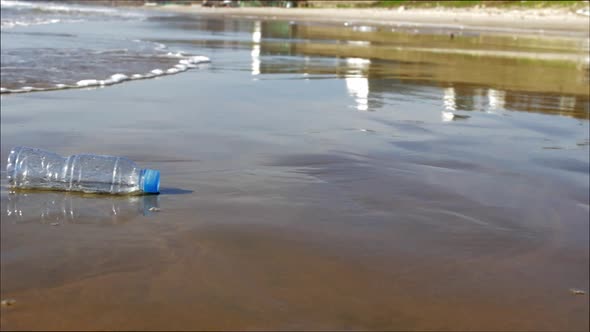 Plastic Bottle Lying on a Sandy Beach in the Water