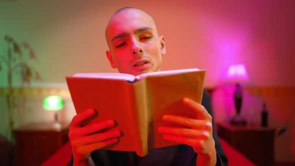 Portrait of Young Man in Dress Reading Closing Book and Looking at Camera with Sad Facial Expression