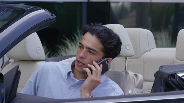 Young businessman sitting in car talking on cell phone