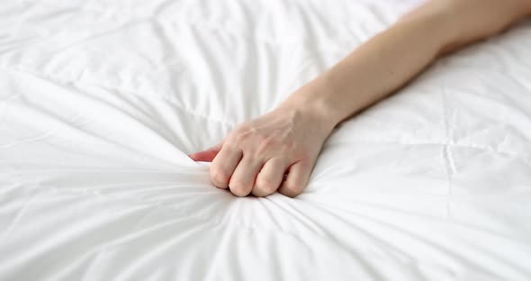 Woman Hand Clutches Blanket on Bed in Pain