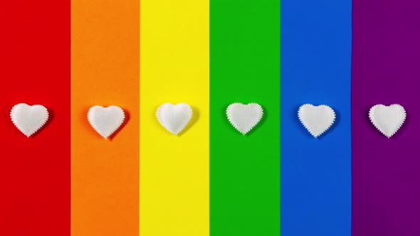 Six small white hearts appear and disappear on LGBT flag background.
