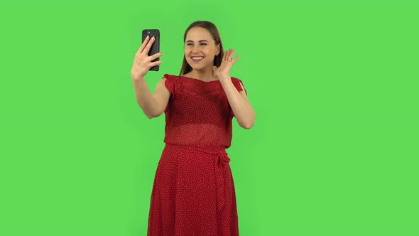 Tender Girl in Red Dress Is Talking for Video Chat Using Mobile Phone and Rejoice. Green Screen