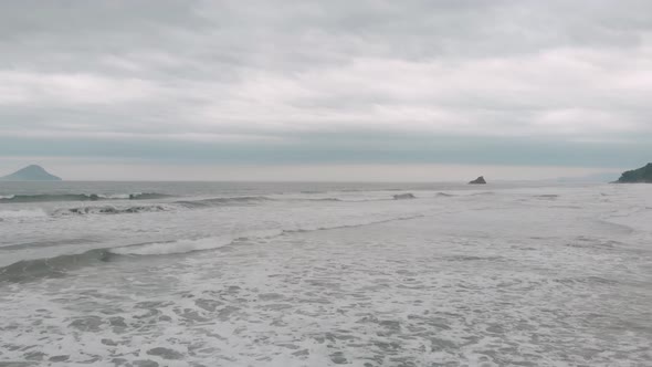 Lateral drone footage of the beach, cloudy day, waves, agitaded sea, landscape of Juquehy, Ubatuba,