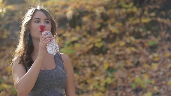 Slim young woman drinking water after training, fitness.