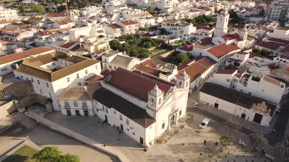 Aerial of Igreja de Santo António that sits across from a castle and watchtowers in Lagos Portugal