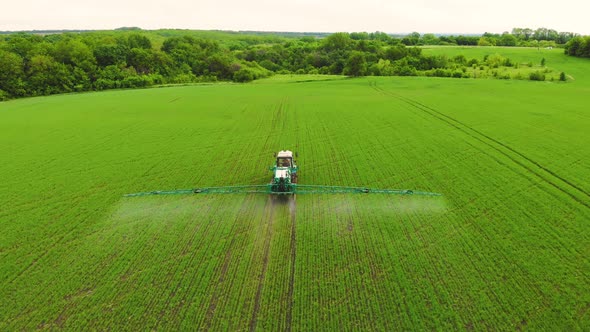 Aerial View of Farming Tractor Spraying on Field with Sprayer Herbicides and Pesticides at Sunset