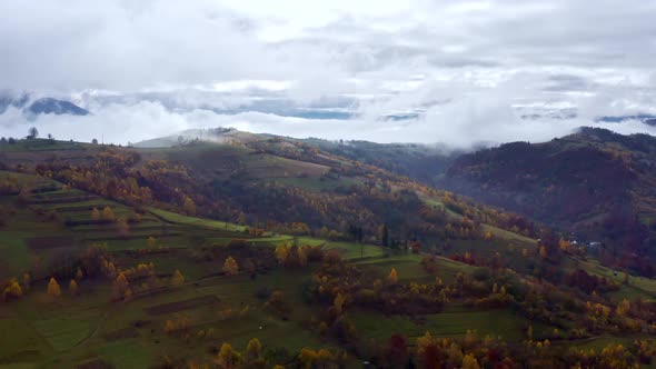 Flu Over Landscapes of Green Hills Under a Layer of White and Fluffy Clouds