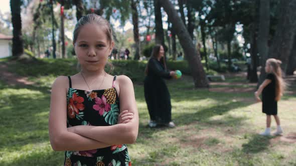 A Little Girl Stands Aside and Offended While Her Family is Playing Ball