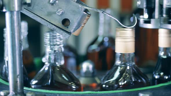 Factory Mechanism is Putting Caps Onto Liquor Bottles