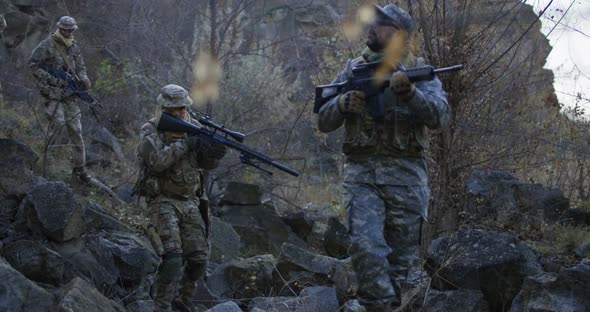 Armed Soldiers Walking Through Rocks at Dusk alt