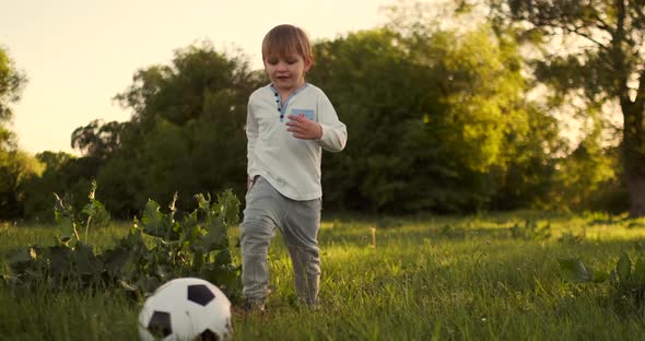 Happy Boy Running with Soccer Ball Running at Sunset in Summer Field