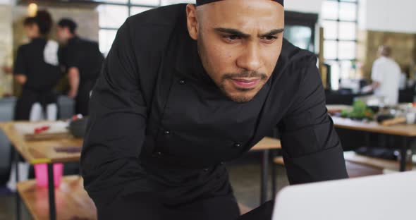 Mixed race male chef using a laptop