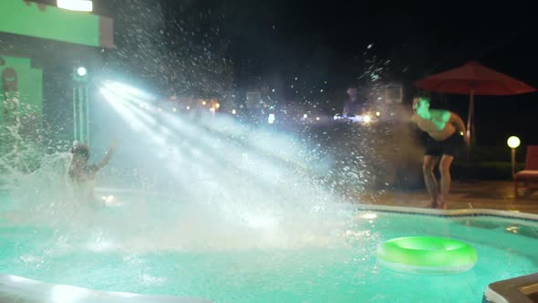 Group of Young Beautiful Topless Adults Jumping at Pool Smiling at Outdoors Night Pool Party While