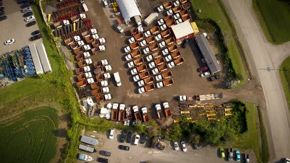 A parking lot full of trucks outside of a large industrial facility.