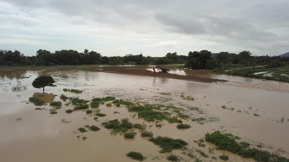 Fly toward excavator near river ban widening project.