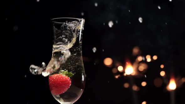 Champagne flute and strawberry splashing with sparklers fireworks