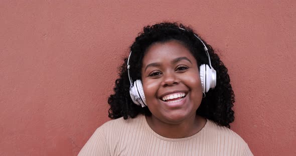 Happy young african woman talking on a video call while wearing headphones