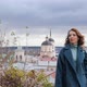 Young Redhaired Woman in a Blue Coat and Walks Against the Backdrop of the Old City - VideoHive Item for Sale