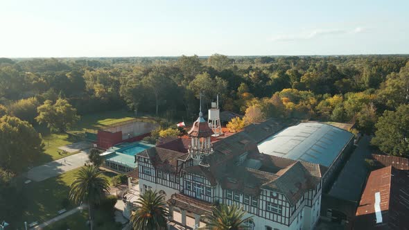 Aerial dolly in over Tigre private rowing club building and swimming pool near de la Plata river at