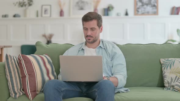 Young Man Closing Laptop Standing and Leaving Sofa