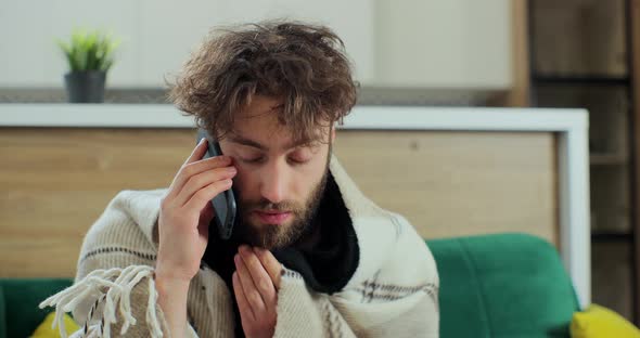 Portrait of Sick Man Sitting in Room and Talking on the Phone While Sitting on the Sofa