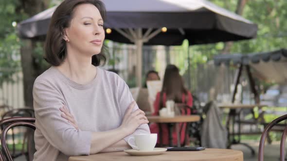 Serious Old Woman Looking in Camera While Sitting in Outdoor Cafe