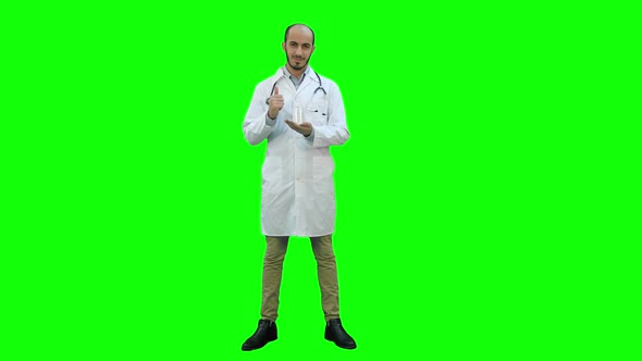 Smiling Doctor Recommending Pills and Giving Thumb Up on a Green Screen, Chroma Key