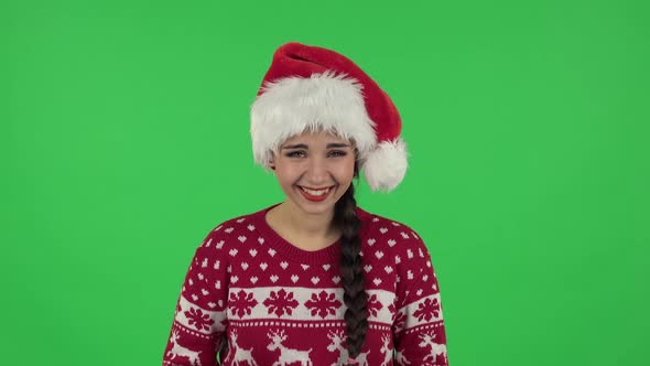 Portrait of Sweety Girl in Santa Claus Hat Is Listening To Boring Information and Smiling Slyly