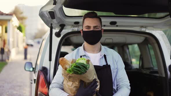 A Movement Shot of a Delivery Man Wearing Protective Face Mask Carrying Groceries Standing Outdoors