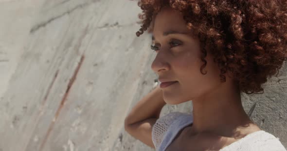 Side view of young African american woman relaxing on beach in the sunshine 4k