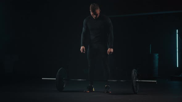 Man in Sport Gym Takes a Heavy Barbell to Train and Pump Muscles on Arms