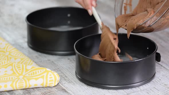 Cake batter pouring into baking dish. Home baking. Woman pour dough into round baking pan.	