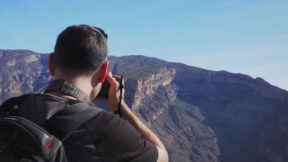 Young Foreign Male Tourist Taking Photos on Professional Camera of Wadi Ghul Aka Grand Canyon of