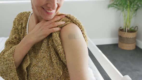 Animation of happy caucasian senior woman showing plaster after vaccination