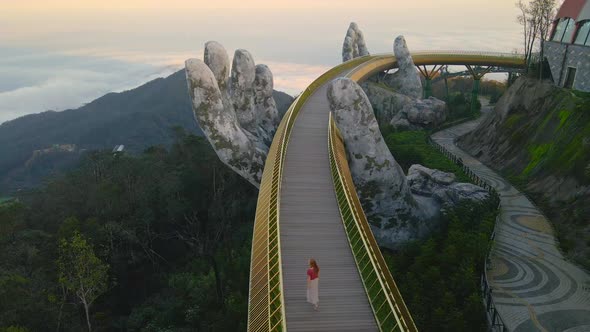 Slowmotion Aerial Shot of a Young Woman Walking on the Golden Bridge in the City of Danang