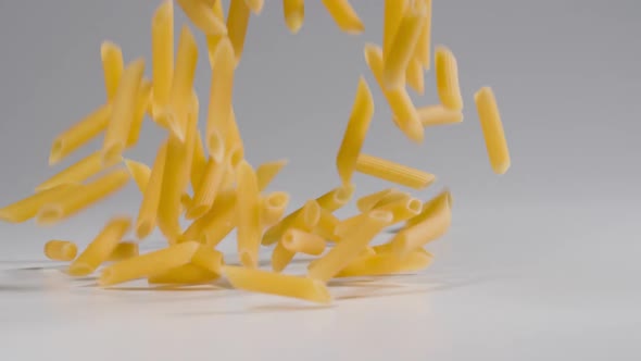 Pasta falling onto a white surface in slow motion