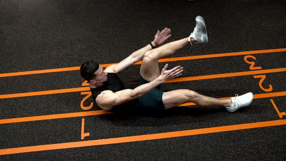 Athletic Man in Sportswear Doing Raisedleg Situp and Clap Exercises on Gym Floor Exercising