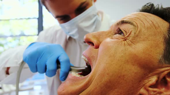 Dentist examining a male patient with tools