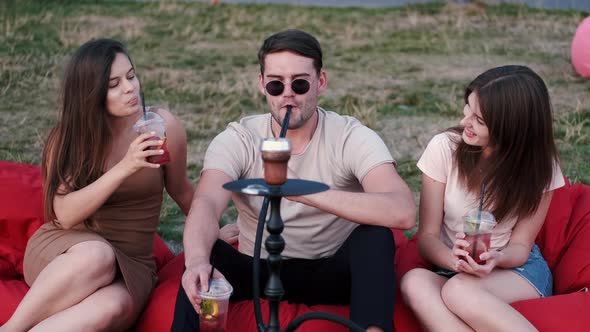 The Young Man Smoking Hookah and Ladies Are Having Fun