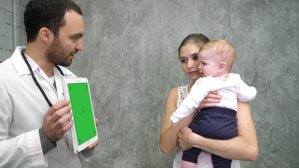 Doctor showing medical results on a tablet to mother and alt