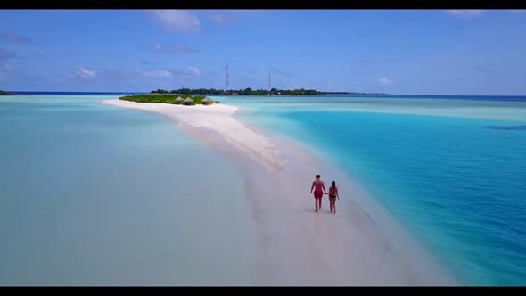 Two people relax on tropical shore beach break by aqua blue sea with white sand background of the Ma