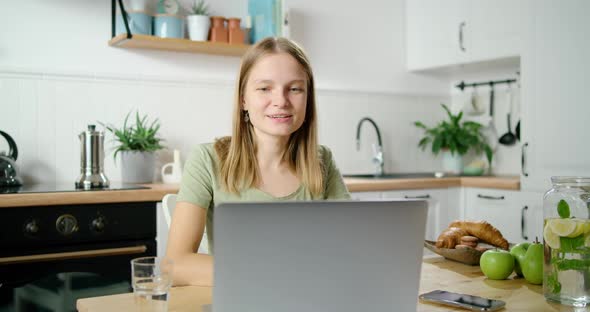 Woman Makes Video Call, Greets Friends and Talks Online Using Laptop in Kitchen