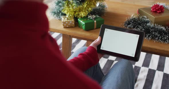 Happy albino african american man wearing santa hat using tablet with copy space at christmas