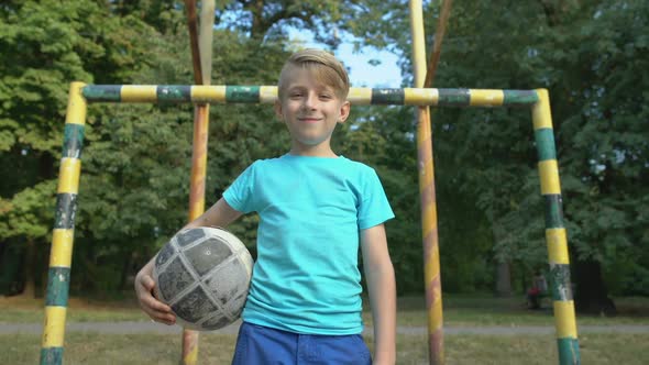 Laughing Boy Goalkeeper Looking Into Camera, Standing With Ball at Pitch, Hobby