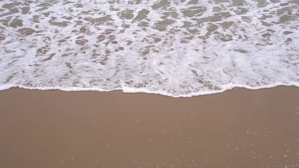 Calm evening ocean surf. Foamy waves fill the sandy beach.