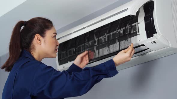 female technician service removing air filter of the air conditioner for cleaning